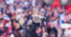 A microphone in front of a crowd showcasing populism
