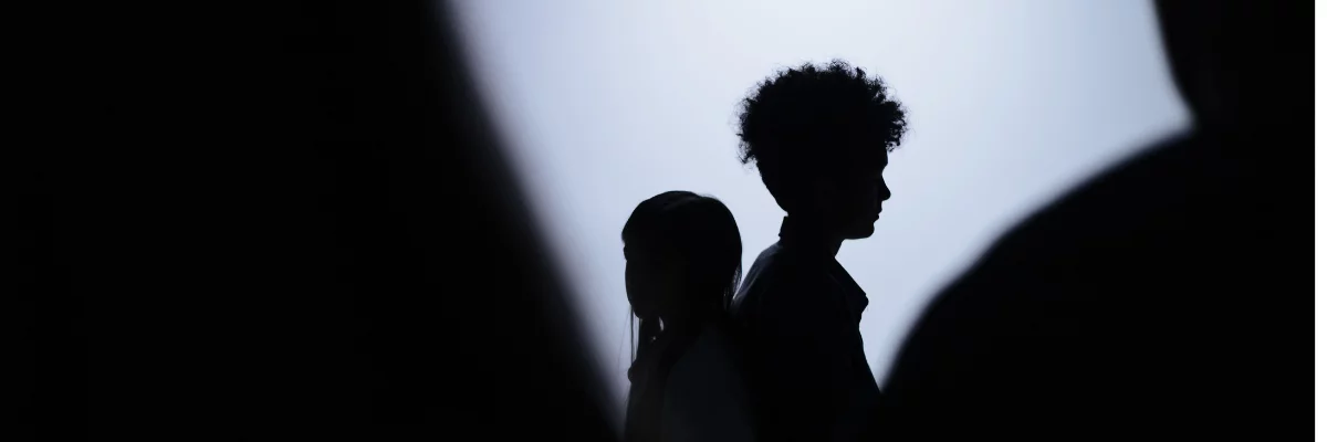 A silhouette of a young boy and girl behind a group of people.