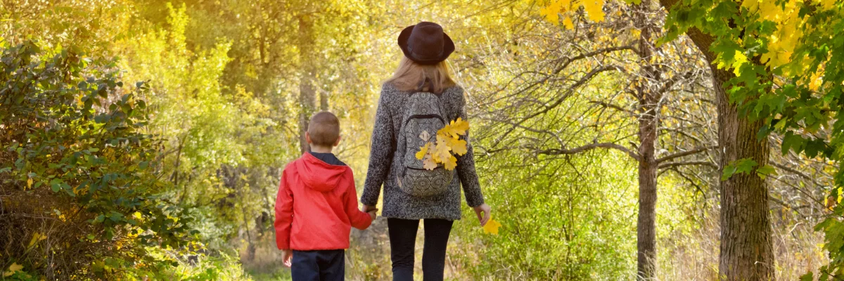 a boy holding his mother's hand in a forest