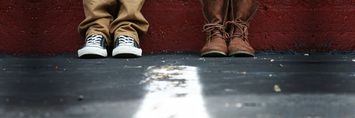 The shoes of a man and a woman divided by a line.