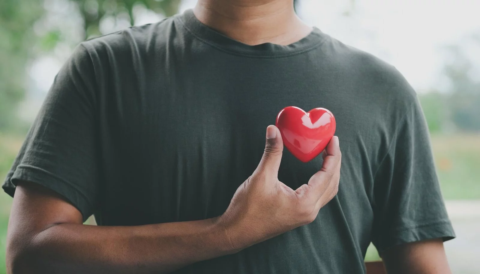 A man holding a toy heart next to his chest.