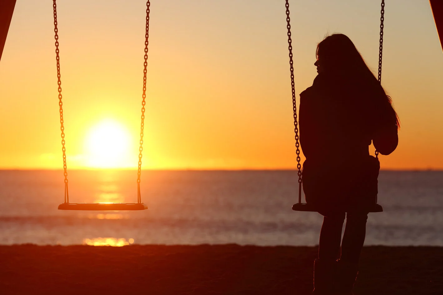 Single woman alone swinging on the beach and looking the other seat missing a boyfriend 2026/02/AdobeStock_84692164_1.jpeg 