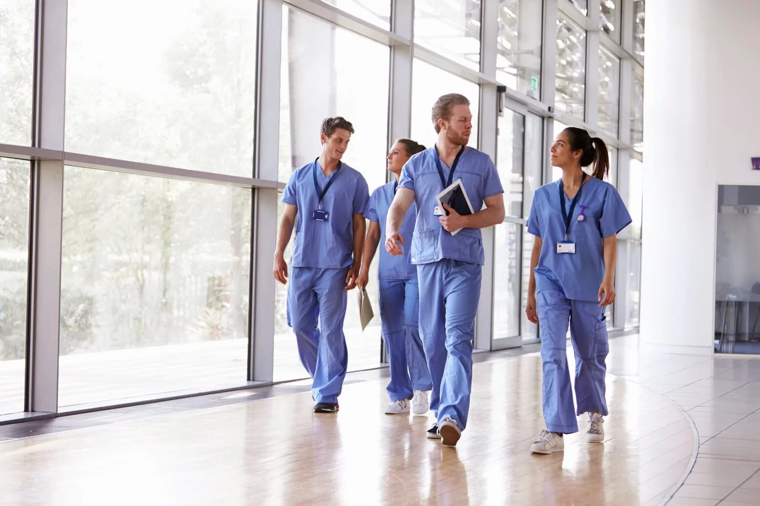 A group of male and female nurses in scrubs walking at work