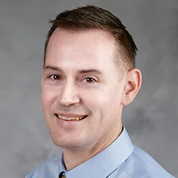 A professional headshot of Shane Kraus in business attire.