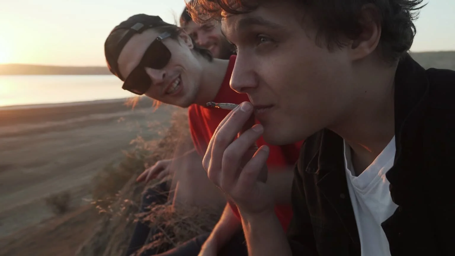 A group of men smoking a marijuana joint at the beach.