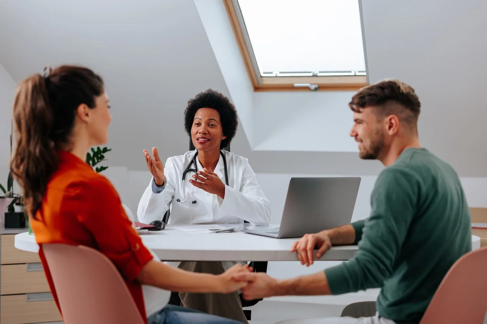 A couple sitting at a table with a doctor for a vasectomy consultation.