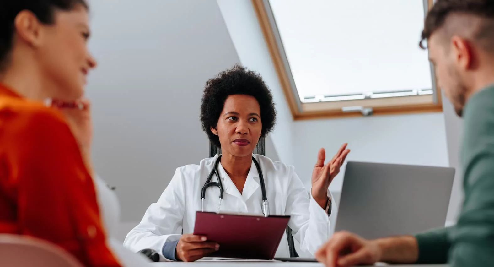 A couple sitting at a table with a doctor for a vasectomy consultation.