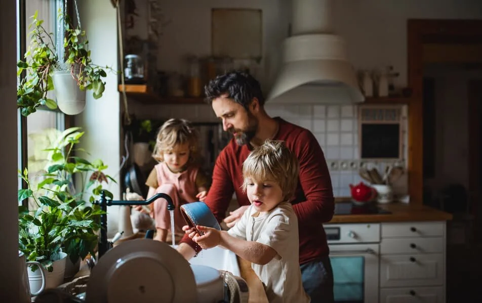 A father doing the dishes with his two children.