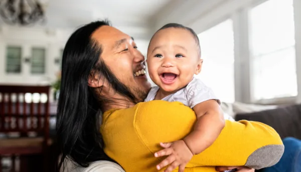 Father holds baby as they both smile