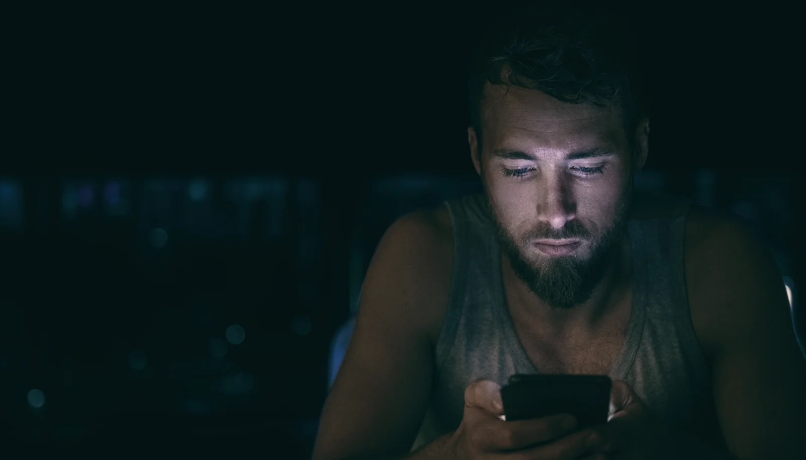 Man looking at phone in a dark room