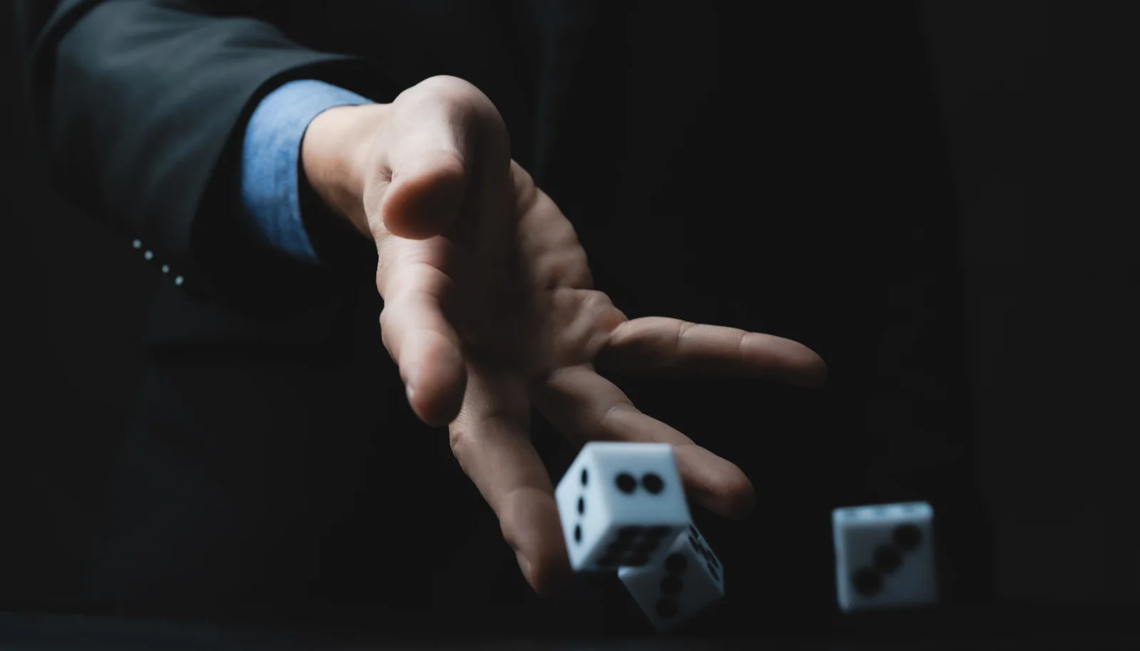Person rolling dice in a dark room