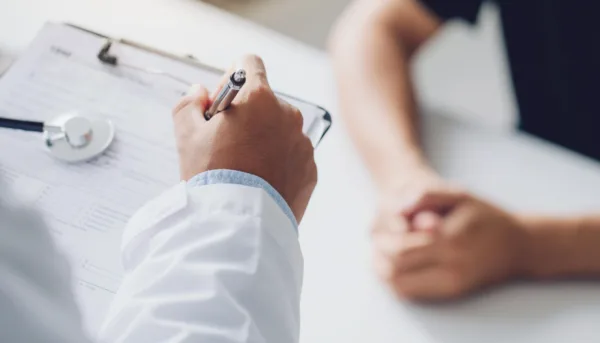 Doctor fills out form while seeing patient