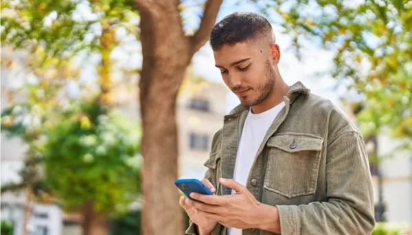 Young man walking with phone in hand